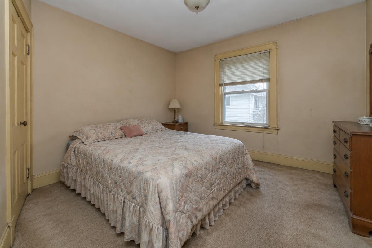 Bedroom before painting with beige walls and worn trim